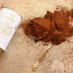 Kakao prah Azbuka. Ambalaža a pored nje se vidi kako prah, paprika i kašikica