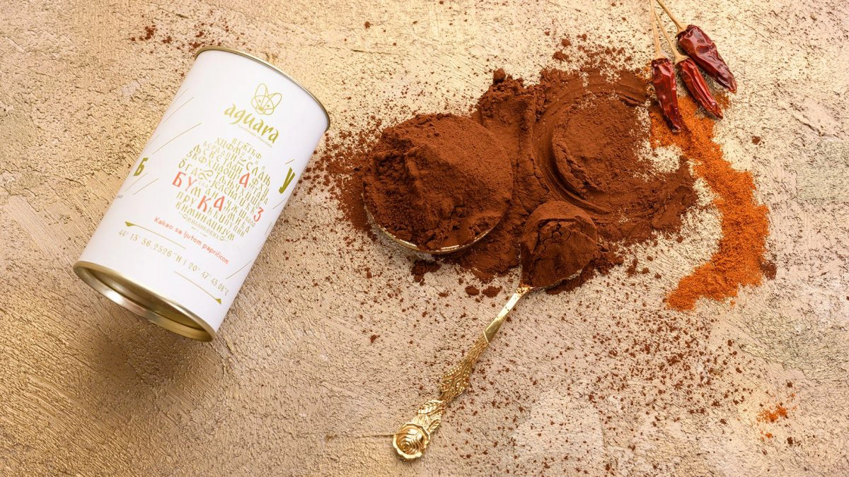 Kakao prah Azbuka. Ambalaža a pored nje se vidi kako prah, paprika i kašikica