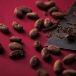 Crvena pozadina na kojoj se nalaze pečena zrna kakaoa