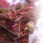 Mlečna čokolada sa malinom, višnjom i laticama ružesa levestrane a sa desne strane se nalaze hemijske formule.