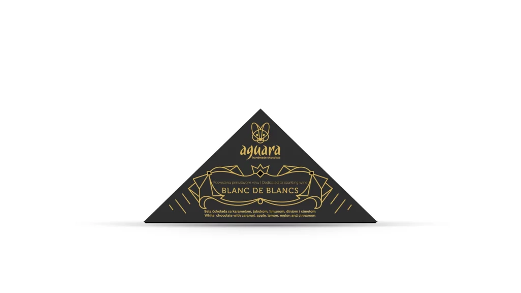 Trouglasta čokolada čokoladeposvećene vinu Blanc de Blancs. Na ambalaži se nalaze linijski elementi koji predstavljaju elemente srpske tradicije.