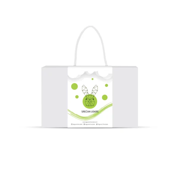 Srećan Uskrs poklon pakovanje Aguara chocolate. Bela kutija sa trakom koja ima kanap umesto drške. Na traci se nalazi linijski iscrtan zeka. Iznad njega se nalaze oblaci a ispod njega zakrivljene zelene linije. Oko zeke se nalaze zeleni krugovi .